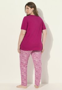 Roze katoenen pyjama set bestaande uit een T-shirt met korte mouwen en een broek met een patroon in een paisley ontwerp in verschillende tinten roze.
