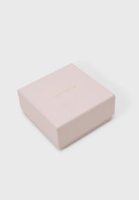 Τετράγωνο, απαλό ροζ κουτί δώρου με χρυσό λογότυπο «Coccinelle» στο καπάκι. Λείο υλικό, διπλωμένες άκρες και καθαρός σχεδιασμός.