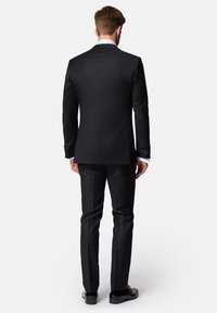 Czarny marynarka i spodnie w dopasowanym kroju, gładka tkanina, slim fit, pojedynczy tylny rozporek, zestawione z czarnymi eleganckimi butami, ukazującymi czyste linie.