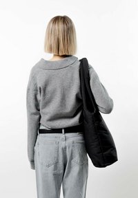 Grå stickad tröja med bred krage, i kombination med ljusblå jeans. En svart axelväska hängs över axeln, med en enkel design.