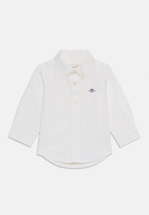 Weißes langärmeliges Hemd aus Baumwolle. Verfügt über einen Button-Down-Kragen, Frontknöpfe und ein kleines gesticktes Logo auf der Brust. Abgerundeter Saum.