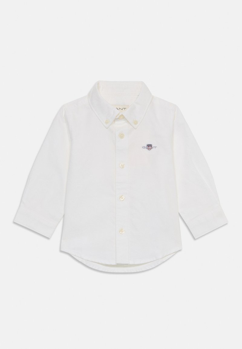 Camicia a maniche lunghe bianca in cotone. Presenta un collo con bottoni, bottoni frontali e un piccolo logo ricamato sul petto. Orlo arrotondato.