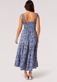 Maxikleid im blauen Blumenmuster mit gerafftem Oberteil und Rüscheträgern; fließender Stoff, knielang und rückenfreies Design.