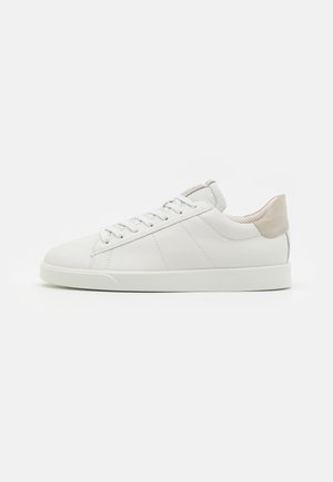 Adidași din piele albă cu o suprafață netedă, vârf rotund și detaliu din suede gri deschis la călcâi, având o talpă plată din cauciuc.
