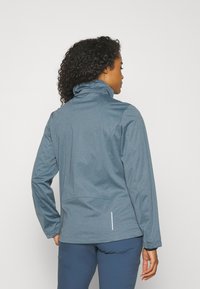 Blue soft-shell jacket with a high collar, long sleeves, and a textured fabric. Features a rear pocket and reflective accent.