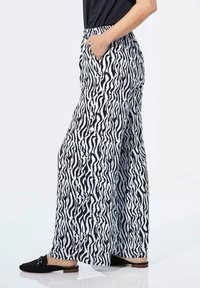 Zwart-witte zebra print wijde broek met een comfortabele elastische tailleband. Heeft zijzakken en een gladde stofstructuur.
