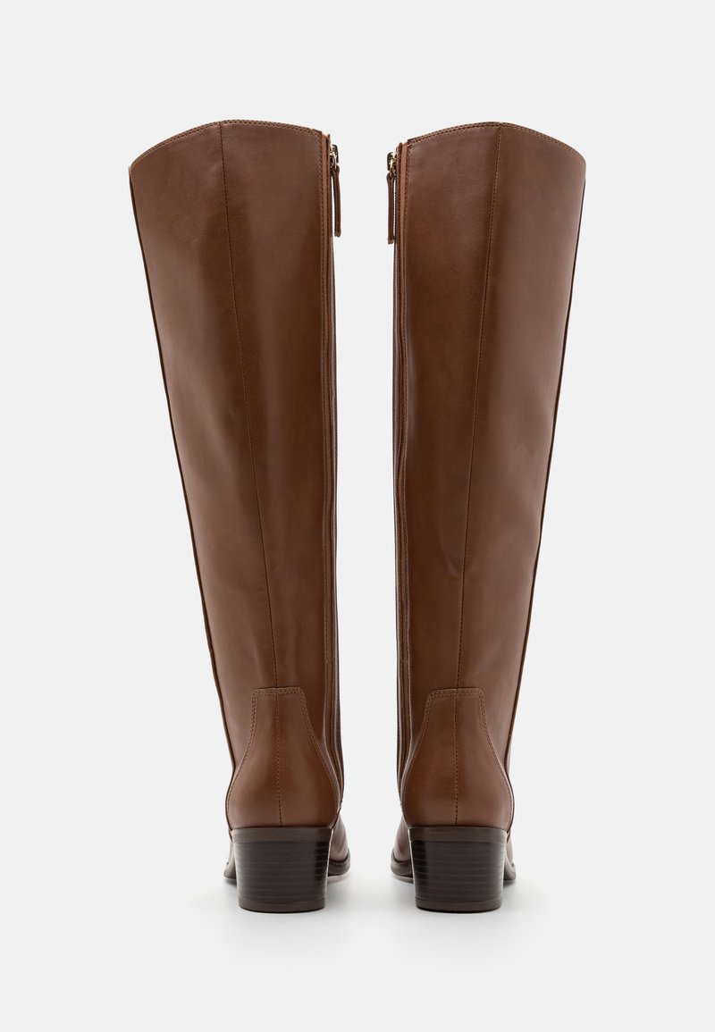 Bottes en cuir marron montantes avec un petit talon, dotées d'une texture lisse, de fermetures éclair sur les côtés et de détails de couture minimalistes.