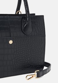 Czarna torebka z ekoskóry o fakturze krokodyla, z złotymi elementami, odpinanym paskiem i usztywnionym kształtem.