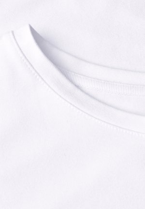 Gros plan d’un t-shirt blanc à col rond montrant les détails des coutures et la texture du tissu.