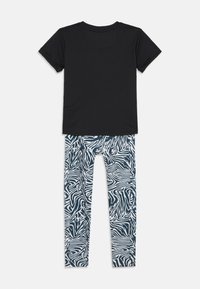 T-shirt noir à manches courtes associé à un legging rayé zèbre bleu marine et blanc, offrant une texture douce et une coupe décontractée.