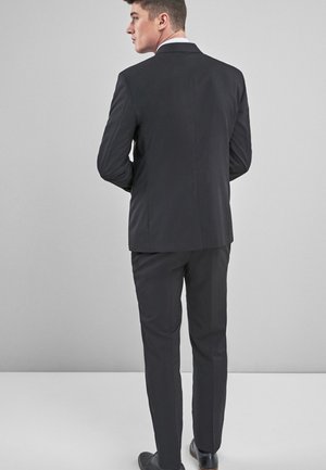 Dark gray suit with a tailored fit, featuring a single vent and straight-leg trousers. Smooth texture, paired with black shoes.