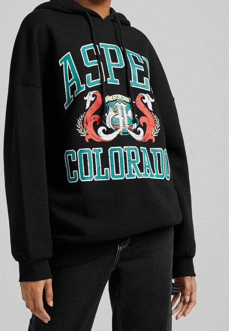 Felpa nera con cappuccio con la scritta "ASPEN COLORADO" in grande formato turchese e rosso. Il design grafico include elementi decorativi. Tessuto morbido.