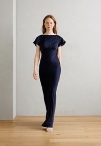 Rochie ajustată, de culoare albastru marin, realizată dintr-un material neted. Dispune de mâneci scurte, cu volan și talie plisată, alunecând până la podea. Design simplu.