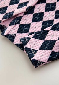 Pikowana koszula w różowo-granatowy wzór w romby, z diagonalnymi liniami i guzikami. Materiał ma teksturowane, żeberkowe wykończenie.
