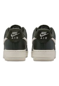 Nike Air-sneakers med ovandel i mörkgrönt läder, beige detaljer, vadderad krage och texturerad gummisula. Logotyp visas på hälen.