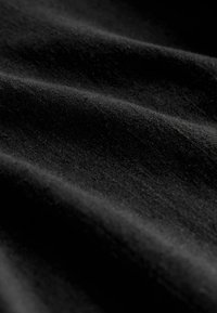 Tissu noir doux avec des plis légers et une texture légèrement duveteuse en gros plan.
