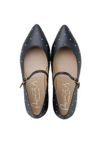 Bailarinas de cuero negro con acentos de tachuelas doradas, puntera puntiaguda y una única correa ajustable sobre el empeine, suela plana.