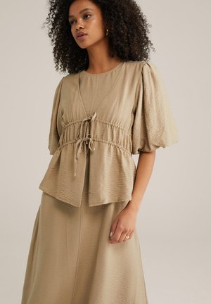 Light beige, textured top with puff sleeves, drawstring waist, and layered hem. Paired with a matching skirt in the same fabric and color.