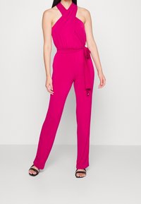 Fuchsia jumpsuit met een halternek, een strik taille en rechte pijpen. Gladde stof met een uniforme textuur en zonder zichtbare patronen of hardware.
