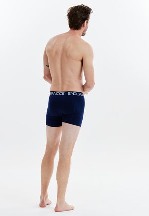 Mörkblå boxerkalsonger med ett vitt elastiskt midjeband som har texten "ENDURANCE". Tyget ser slätt och åtsittande ut och visar en skräddarsydd design.