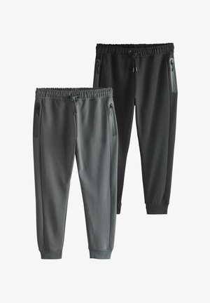 Dwie pary spodni dresowych w różnych odcieniach szarości i czerni. Wyróżniają się elastycznymi paskami w talii, zapinanymi kieszeniami oraz ściągaczami przy nogawkach.