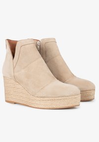 Botas de tobillo con cuña de ante beige, con plataforma de yute estilo espadrille y cremallera lateral. Presentan una textura suave y un diseño inclinado en el empeine.