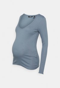 Blusa de maternidade de manga longa em tecido macio e elástico; possui um decote em V profundo e um corte justo, na cor azul suave.