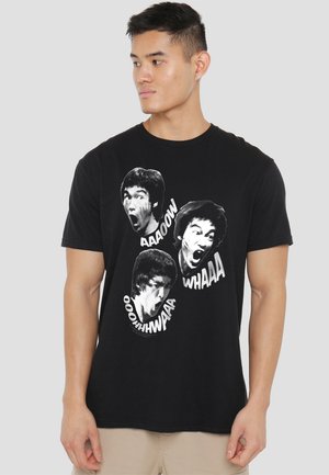 Black cotton t-shirt featuring three large white graphic prints of a person’s face, expressing various emotions with text like "AAOOW" and "WHAAA."