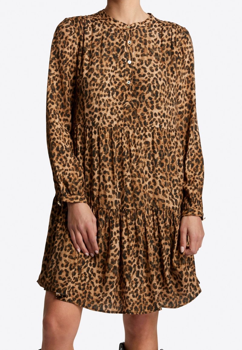 Vestido de leopardo en tonos marrones con mangas largas, cierre de botones en la parte delantera y falda de volantes. Tejido suave con una textura fluida.