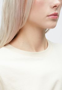 Gai beidzis kokvilnas t-krekls ar klasisku apaļu kakla izgriezumu un īsām piedurknēm, kuram ir gluda tekstūra un minimālisma dizains.