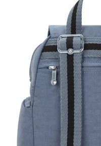 Ljusblå tygryggsäck med ett grått och svart randigt bärband, silverfärgade detaljer och en liten sidofickan med dragkedja.