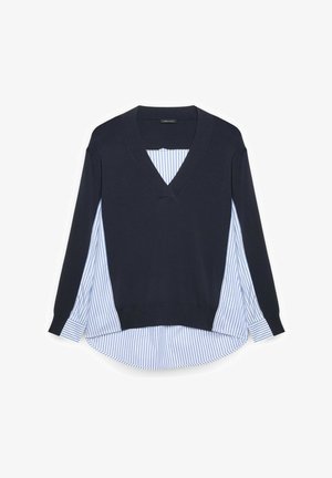 Laivastonsininen V-kauluksinen neulepaita, yllään sinivalkoraidallinen, pitkähihainen paita, jossa on pyöristetty helma.
