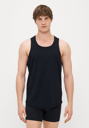 Schwarzes ärmelloses Tanktop mit rundem Halsausschnitt und lockerer Passform. Hergestellt aus glattem, flexiblem Stoff, kombiniert mit schwarzen Shorts.