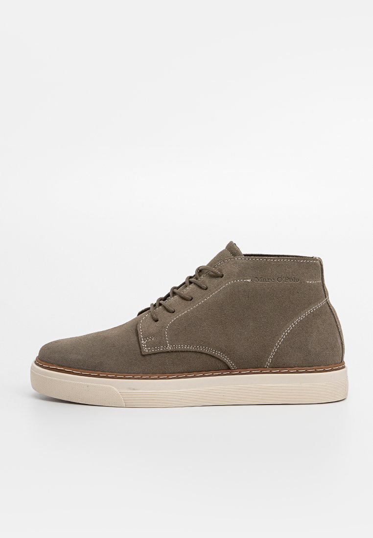 Braune Wildleder-Mid-Top-Sneaker mit beiger Gummisohle, Schnürverschluss und sichtbaren weißen Nähten auf einem weißen Hintergrund.