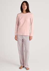Light pink long-sleeve top paired with striped pajama pants featuring vertical navy stripes. Both made from soft, comfortable fabric.