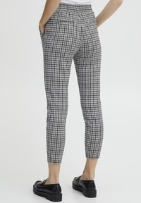 Czarno-białe spodnie w kratę o wysokim stanie, charakteryzujące się dopasowanym krojem, tylnymi kieszeniami oraz gładkim materiałem o eleganckim wyglądzie.