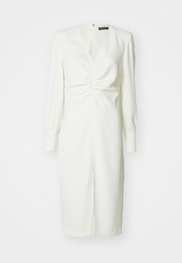 Weißes Kleid mit langen Ärmeln, tiefem V-Ausschnitt, gerafften Details an der Vorderseite und einem Schlitz am unteren Ende. Glatte Textur und figurbetonter Schnitt.