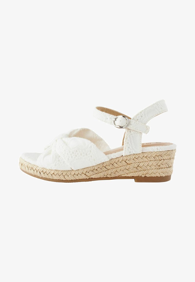Sandales compensées blanches avec une semelle en jute tressé, des brides en tissu présentant un motif texturé et une sangle de cheville réglable avec une boucle en argent.