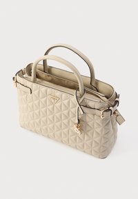 Beżowa pikowana torebka na dwa uchwyty, z złotymi detalami i trójkątnym logo marki. Posiada zamknięcie na zamek błyskawiczny oraz zawieszkę w kształcie klucza.