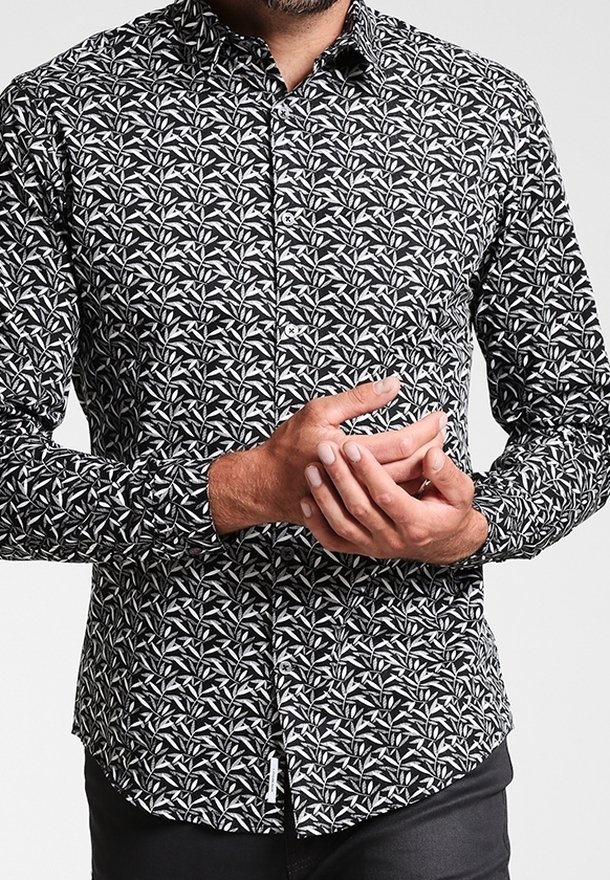 Czarna i biała koszula na guziki z kwiatowym wzorem, długimi rękawami i ostrym kołnierzykiem. Tkanina wydaje się lekka i gładka.