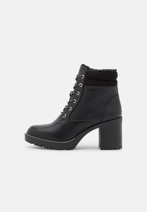 Bottines noires avec une tige en cuir, bout rond, poignet rembourré et un talon épais. Comprend des oeillets en métal et des détails de lacets. Semelle texturée.