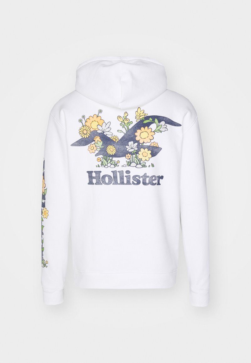 Weißer Hoodie mit Kapuze, der florale Designs in Gelb und Grün zeigt, mit dem Schriftzug "Hollister" in Dunkelblau über den Rücken und Akzenten an den Ärmeln.