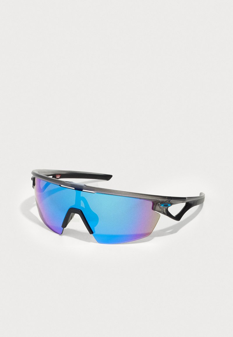 Sonnenbrille mit einem eleganten schwarzen Rahmen, blauen und lila verlaufenden Gläsern, kantigem Design und sichtbarem Markenlogo an der Seite.