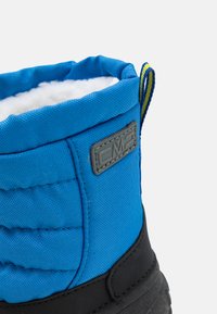 Stivaletto in tessuto blu con design trapuntato e suola in gomma nera. Presenta una patchlogo grigia e un rivestimento in pile testurizzato nella parte superiore.