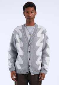 Gray cardigan with contrasting zigzag pattern in lighter gray. Features a v-neckline, ribbed cuffs, and buttons down the front.