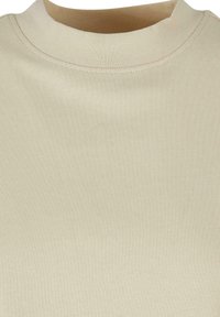 Camisa de cuello redondo beige claro con una textura acanalada, que presenta una costura lisa a lo largo del cuello. Sin patrones visibles ni detalles metálicos.