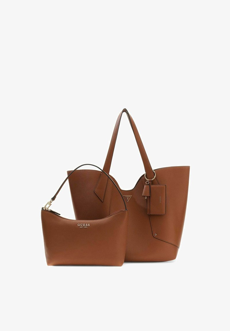 Deux sacs à main en cuir marron de la marque Guess, un grand cabas avec doubles poignées et étiquette attachée, un sac bandoulière plus petit avec fermeture éclair.