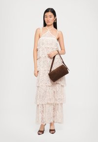 Lace jurk in lichtroze met gelaagde volants, verstelbare banden, gecombineerd met een bruine leren handtas en bruine sandaaltjes met hak.