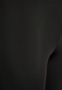 Nærbillede af glat, mørk sort stof, der viser fin tekstur og subtile lysreflektioner.