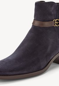 Bottine en daim gris foncé avec talon bas empilé et sangle en cuir marron ornée d'une petite boucle dorée.